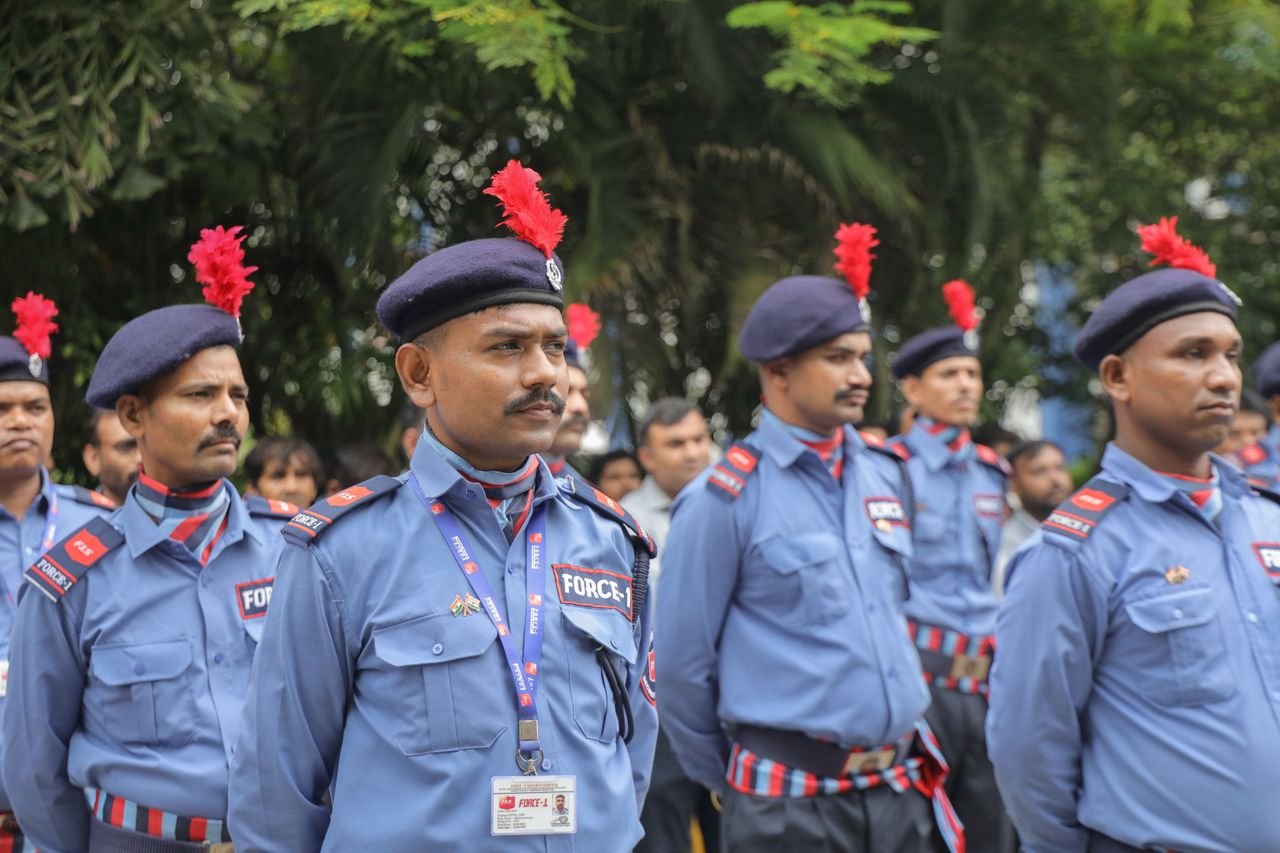 Security personnel in uniform standing in formation with serious expressions outdoors.